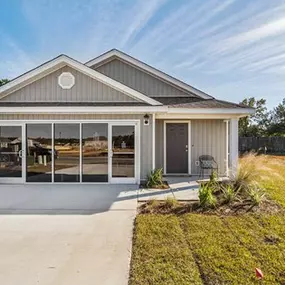 A home with large glass doors and a grassy yard