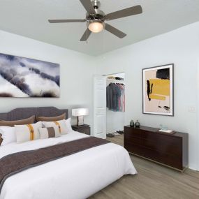 Bedroom with walk in closet wood look flooring and ceiling fan