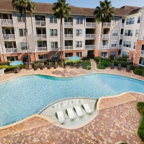 Resort style swimming pool daytime palm trees at Camden Heights Apartments in Houston, TX