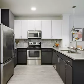 Kitchen with quartz countertops, stainless steel appliances, white upper cabinets and gray lower cabinets at Camden Heights Apartments in Houston, TX