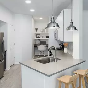 Kitchen with concrete-look countertops, pendent lights, bar seating and built-in desk to work or study from home at Camden Heights Apartments in Houston, TX