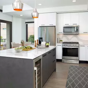 Bright contemporary finishes kitchen with stainless steel appliances and quartz countertops