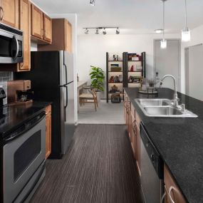 Kitchen with large island, black quartz countertops, gray subway-tile backsplash and stainless steel appliances