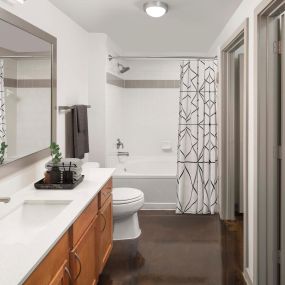 Bathroom with concrete floors, white countertops, and large soaking bathtub at Camden Design District