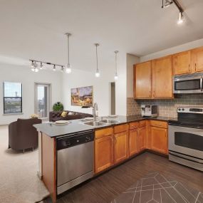 Kitchen with granite countertops wood look flooring and stainless steel appliances