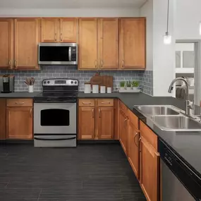 Spacious kitchen with black granite countertops, gray subway tile backsplash and stainless steel appliances at Camden Design District apartments in Dallas, TX