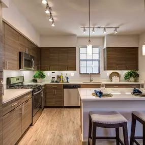 Open concept kitchen with stainless steel appliances white quartz countertops and barstool island seating