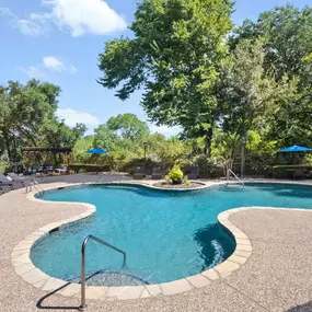 Resort-style pool surrounded by trees at Camden Legacy Creek apartments in Plano, TX