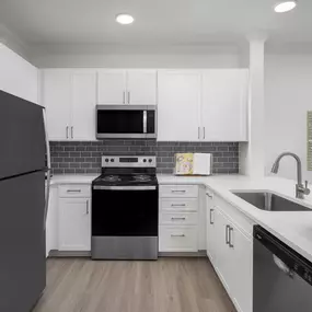 White shaker cabinetry, white quartz countertops, gray subway tile backsplash and stainless steel appliances at Camden Northpointe apartments in Tomball, Tx.