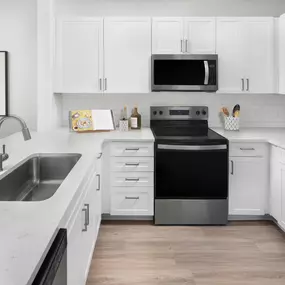 Kitchen with white quartz countertops, stainless steel appliances and white subway tile backsplash at Camden Northpointe Apartments in Tomball, Tx