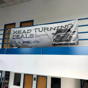 Jeff Wyler Chrysler Dodge Jeep Ram of Lawrenceburg, Indiana interior showcased in this photo, featuring a “Head Turning Deals” sign that highlights the dealership’s ongoing savings and special offers on Chrysler, Dodge, Jeep, and Ram vehicles.