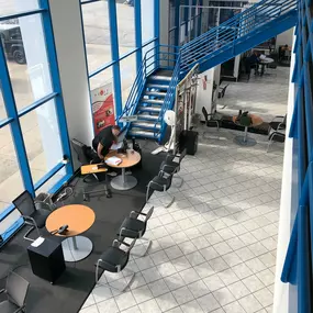 Jeff Wyler Chrysler Dodge Jeep Ram of Lawrenceburg, Indiana interior showcased in this photo, featuring a comfortable seating area and modern staircase that provide a welcoming and professional atmosphere for customers visiting the dealership.