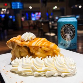Apple Pie topped with whipped cream and a caramel drizzle.