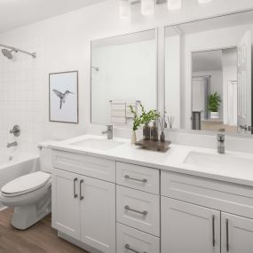 Bathroom with two sinks, white marbled quartz countertops, white cabinets, and soaking bathtub at Camden Stoneleigh apartments in Austin, TX.