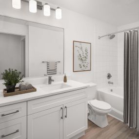 Bathroom with wood-style flooring, white marbled quartz countertops, white cabinets, and soaking bathtub at Camden Stoneleigh apartments in Austin, TX.
