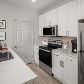 Kitchen with white marbled quartz countertops, stainless steel appliances, and white cabinets at Camden Stoneleigh apartments in Austin, TX.