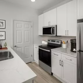 Kitchen with white marbled quartz countertops, stainless steel appliances, and white cabinets at Camden Stoneleigh apartments in Austin, TX.