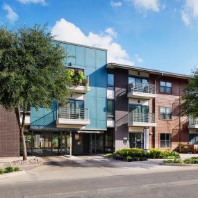 Building exterior showing private balconies and gated parking entrance