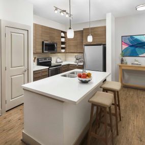 Kitchen with breakfast bar and wood-style flooring at Camden Lincoln Station Apartments in Lone Tree, CO