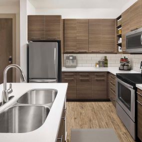 Kitchen with white quartz countertops and stainless steel appliances at Camden Lincoln Station Apartments in Lone Tree, CO
