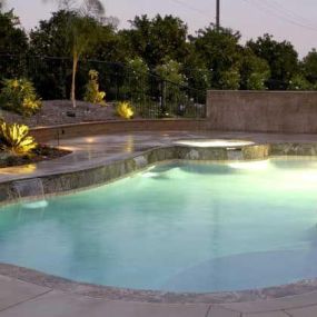 Custom inground pool at night with pool lighting