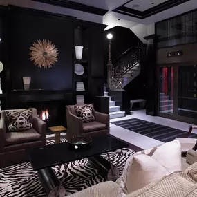 XV Beacon, a luxury Hotel in Boston. View of a lounge near the elevators. The room is dimly lit, has comfy furniture, and ambient lighting.