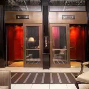 XV Beacon, a luxury Hotel in Boston. View of a lounge near the elevators. The room is dimly lit, has comfy furniture, and ambient lighting.