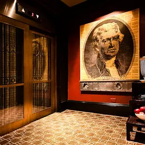 XV Beacon, a luxury Hotel in Boston. View of a lounge near the elevators. The room is dimly lit, has comfy furniture, and ambient lighting.
