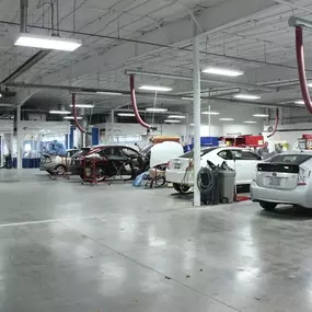 The image depicts the spacious and well-organized interior of the Ball Body Shop’s repair facility