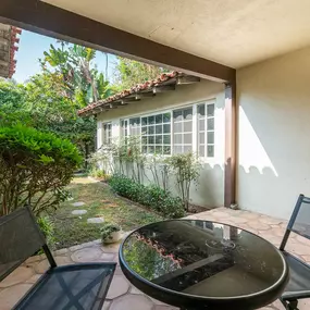 Covered outdoor patio with cushioned seating and garden views, offering a quiet space for clients to relax or connect.
