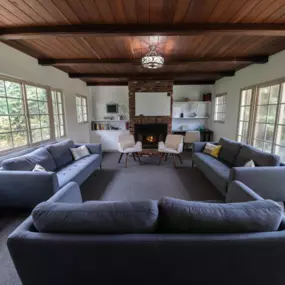 Group therapy room with circular seating arrangement, cozy fireplace, and warm lighting.