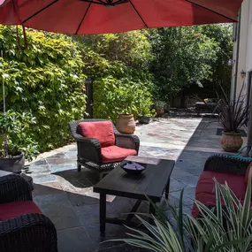 Outdoor seating area with chairs and umbrella, providing shade and relaxation at Clearview’s gender-inclusive mental health center.