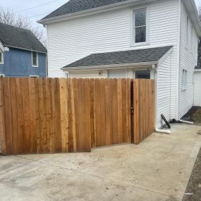 wood privacy fence and gate through concrete driveway