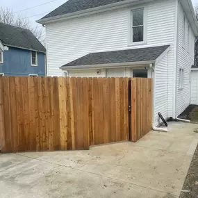 wood privacy fence and gate through concrete driveway