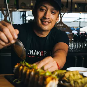 A Temaki Bar sushi chef putting the finishing touches on a specialty sushi roll.