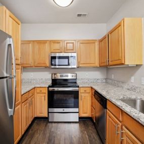 Gourmet Kitchens with Raised Panel Cabinetry, Granite Like Countertops, Black Appliance Packages and Undermount Lighting at Cambridge Square Apartments