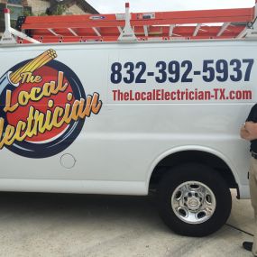 A Local Electrician technician standing in front of their van with the logo, phone number, & website on the side