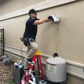 Technician working on a ladder for exterior lighting installation