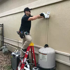 Technician working on a ladder for exterior lighting installation