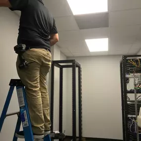 One of The Local Electrician's technicians performing electrical services standing on a ladder in a drop ceiling