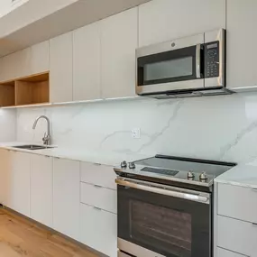 A modern kitchen with a stainless steel refrigerator, microwave, and oven
