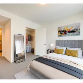 A bedroom with a large bed and a painting on the wall