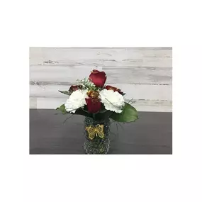 This simple, yet elegant arrangement of red glittered roses in beautiful glass container adorned with a butterfly is sure to bring smiles and warmth to anyone.