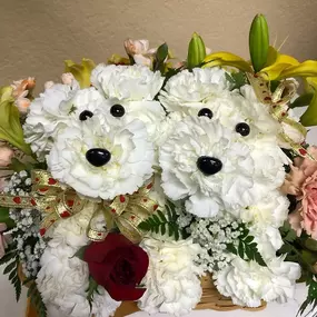 Our Cute Couple - What's more adorable than a puppy made out of Carnations? TWO Puppies made out of Carnations! Our Cute Couple is set in a cute wicker basket with sweet-scented Baby's Breath, Lilies and Carnations, and each puppy is adorned with a ribbon.