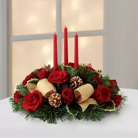 The Celebration of the Season™ Centerpiece is a grand display of holiday elegance. Red roses and spray roses pop against a backdrop of assorted holiday greens and variegated holly that beautifully encircle three red taper candles. Accented with gold pinecones and gold metallic brocade ribbon, this centerpiece creates a warm and enchanting glow to benefit their holiday festivities.