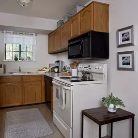 Side close-up of Plymouth Woods Apartments' kitchen area showcasing the sink, oven, and cabinets