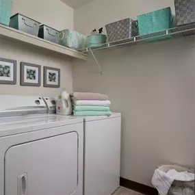 Laundry room of Plymouth Woods Apartments' 2-bedroom apartment for rent with gray and teal them