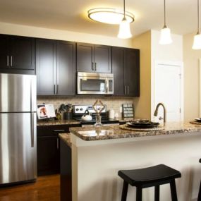 kitchen in model apartment with stainless steel appliances and granite countertops