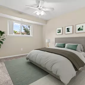 This inviting bedroom at Water’s Edge Apartments in South Lyon, MI features a plush carpeted floor, neutral-toned walls, large window for natural light, and a modern ceiling fan for year-round comfort. The room is styled with contemporary furniture, soft bedding, and calming décor to highlight the relaxing, well-designed space ideal for both rest and retreat.