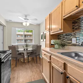 This modern kitchen and dining nook at Water’s Edge Apartments in South Lyon, MI showcases warm wood cabinetry, a sleek tile backsplash, energy-efficient appliances, and a cozy dining space bathed in natural light. The layout is designed to be both functional and inviting, offering residents a stylish and convenient area to cook, dine, and gather with ease.